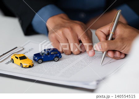 Two people signing car insurance policy document for financial agreement 140554515