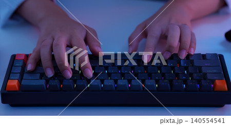 Hands typing on modern backlit keyboard for digital technology work and gaming coding close 140554541