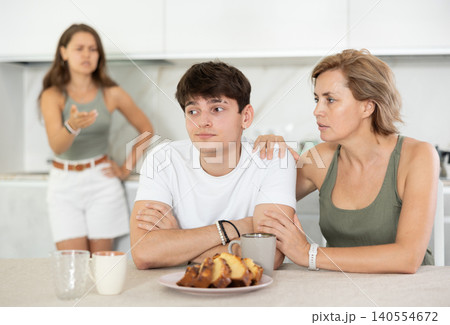 Woman sits near guy and comforts him during quarrel with girl. 140554672