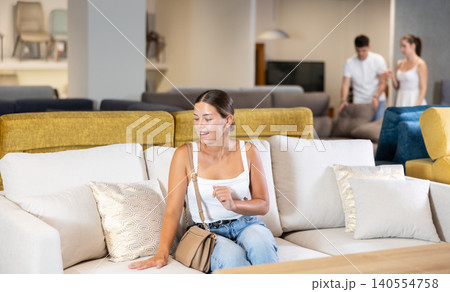 Young girl choosing convenient sofa in furniture shop Young girl choosing convenient sofa in furniture shop 140554758