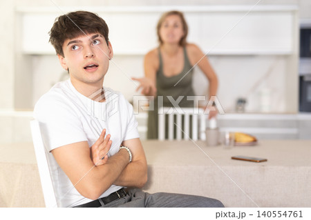 Adult woman quarreling with young guy in kitchen Adult woman quarreling with young guy in kitchen 140554761