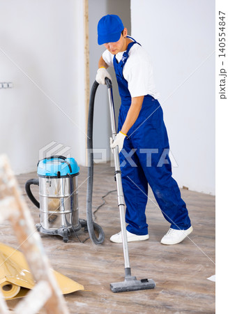 Man vacuums the floor - professional cleaning after renovation in room Man vacuums the floor - professional cleaning after renovation in room 140554847