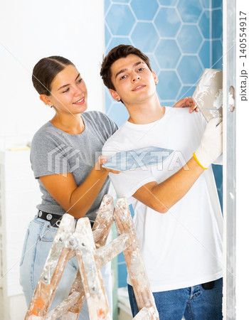 Positive couple working with ceramic tiles for interior wall decoration Positive couple working with ceramic tiles for interior wall decoration 140554917