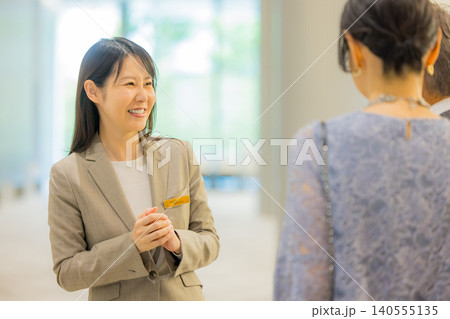 イベントホールに出かけるミドル夫婦を案内するスタッフ イベントホールに出かけるミドル夫婦を案内するスタッフ 140555135