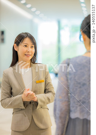 イベントホールに出かけるミドル夫婦を案内するスタッフ イベントホールに出かけるミドル夫婦を案内するスタッフ 140555137