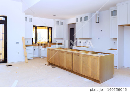 Workers are installing kitchen cabinets countertops in new house room is bright with unfinished details. 140556046