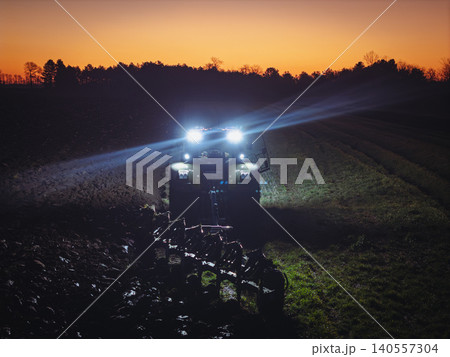 close up Tractor Plowing Field at night with headlights close up Tractor Plowing Field at night with headlights 140557304