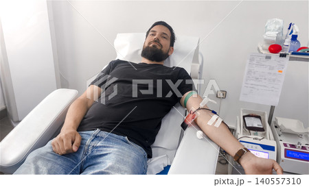 Portrait of Blood donor and Blood donation process. Hand with needle and bag of blood at a blood donation center Portrait of Blood donor and Blood donation process. Hand with needle and bag of blood at a blood donation center 140557310