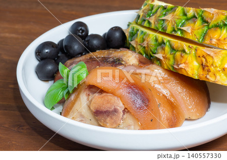 Baked HAM steaks lie on green lettuce leaves, cherry tomatoes, pineapple 140557330
