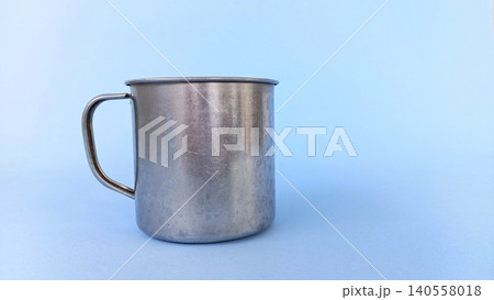 Empty stainless steel cup or mug on blue background. Empty stainless steel cup or mug on blue background. 140558018