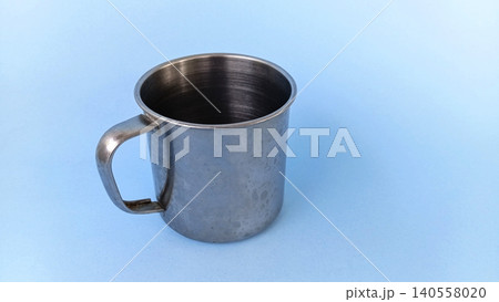 Empty stainless steel cup or mug on blue background. Empty stainless steel cup or mug on blue background. 140558020