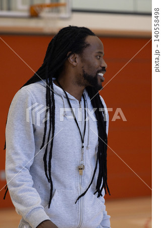 African american man smiling on basketball court wearing zip-up hoodie, whistle lanyard African american man smiling on basketball court wearing zip-up hoodie, whistle lanyard 140558498