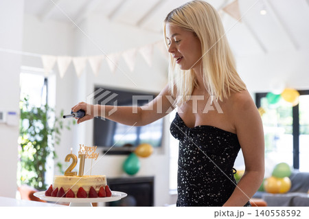 Woman in 20s lighting strawberry birthday cake candle with lighter at home, copy space Woman in 20s lighting strawberry birthday cake candle with lighter at home, copy space 140558592