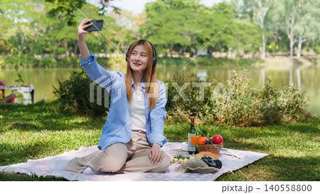 Asian woman in 20s taking selfie during spring picnic in park Asian woman in 20s taking selfie during spring picnic in park 140558800