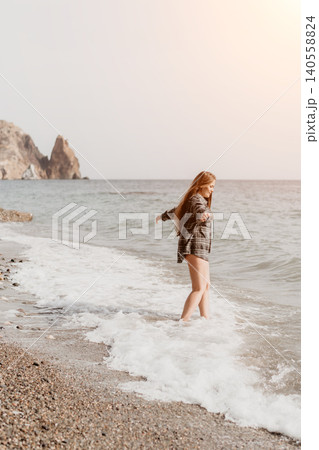 Woman ocean beach scene featuring a young lady in a plaid shirt enjoying the waves and sea spray on a sunny day Woman ocean beach scene featuring a young lady in a plaid shirt enjoying the waves and sea spray on a sunny day 140558824