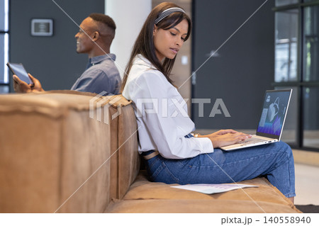 Diverse coworkers working on documents using laptop and tablet in office lounge, copy space Diverse coworkers working on documents using laptop and tablet in office lounge, copy space 140558940