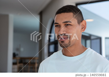 African American man posing in living area wearing white Tshirt near dining table chairs copy space African American man posing in living area wearing white Tshirt near dining table chairs copy space 140559081