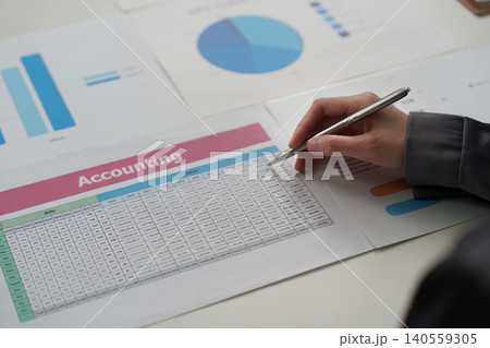 Asian woman in 20s writing notes on accounting document in office Asian woman in 20s writing notes on accounting document in office 140559305