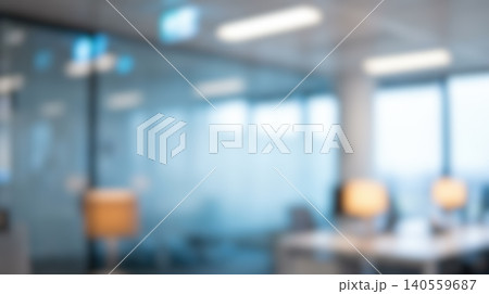 Blurred modern office workspace interior featuring empty desks illuminated by warm lamps alongside glass partitions creating professional business company environment background 140559687