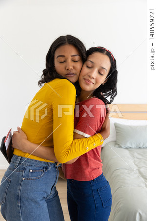 Diverse mom and teenage daughter hugging and comforting each other in bedroom 140559721