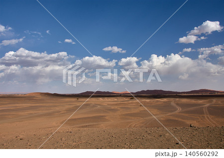 A dirt and gravel track leads towards the fine sand hills of the Merzouga Desert in Morocco. A dirt and gravel track leads towards the fine sand hills of the Merzouga Desert in Morocco. 140560292