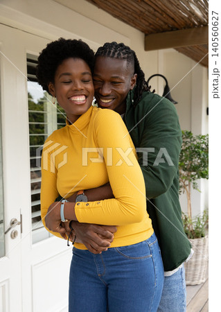 African american couple hugging on porch under wicker canopy beside shuttered french door African american couple hugging on porch under wicker canopy beside shuttered french door 140560627