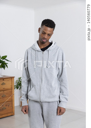 African american man standing near room corner in sportswear by wooden chest and plant 140560779
