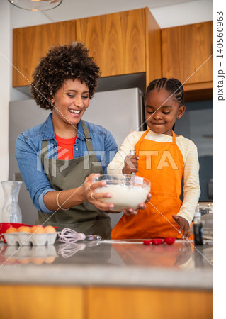 African american mother and daughter mixing batter at kitchen island with bowl, whisk, berries African american mother and daughter mixing batter at kitchen island with bowl, whisk, berries 140560963