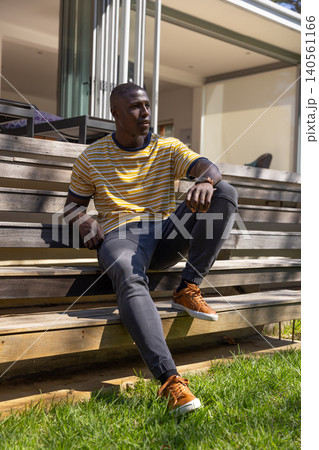 African american adult male sitting on wood deck steps outside home African american adult male sitting on wood deck steps outside home 140561166