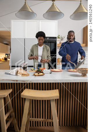 African american couple preparing breakfast on countertop island with sliced avocados in kitchen African american couple preparing breakfast on countertop island with sliced avocados in kitchen 140561240