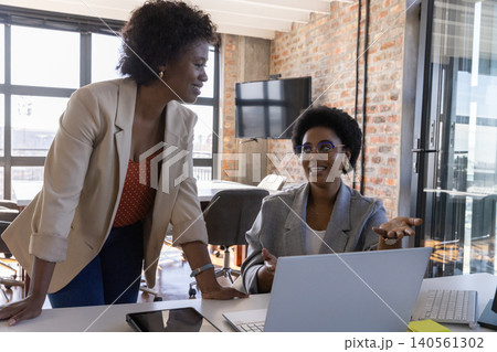 African american women coworkers collaborating in conference room with laptop 140561302
