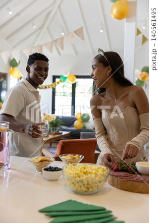 African american couple slicing strawberries at kitchen counter, charcuterie board and balloons African american couple slicing strawberries at kitchen counter, charcuterie board and balloons 140561495