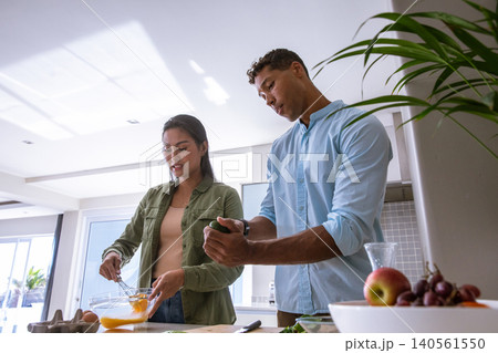Diverse couple whisking eggs, slicing avocado at kitchen island with fresh produce display Diverse couple whisking eggs, slicing avocado at kitchen island with fresh produce display 140561550