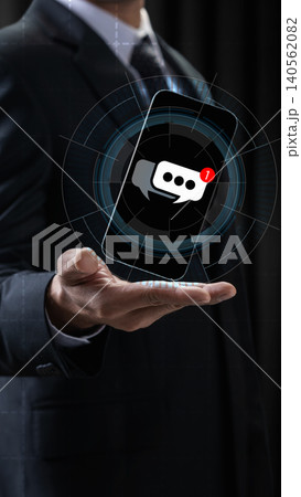 Businessman holding a floating holographic smartphone with a chat message notification icon, symbolizing digital communication and modern business connectivity Businessman holding a floating holographic smartphone with a chat message notification icon, symbolizing digital communication and modern business connectivity 140562082