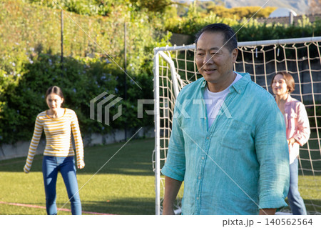 Diverse family standing in front of metal soccer goal net on synthetic turf field Diverse family standing in front of metal soccer goal net on synthetic turf field 140562564