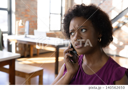 African american woman wearing purple blouse talking on smartphone in office, copy space 140562650