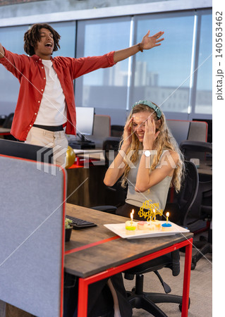 Diverse coworkers celebrating birthday surprise for woman with cake, balloons and monitor in office Diverse coworkers celebrating birthday surprise for woman with cake, balloons and monitor in office 140563462