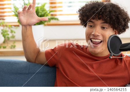Man speaking into microphone with pop filter, leaning on couch in home studio, copy space Man speaking into microphone with pop filter, leaning on couch in home studio, copy space 140564255