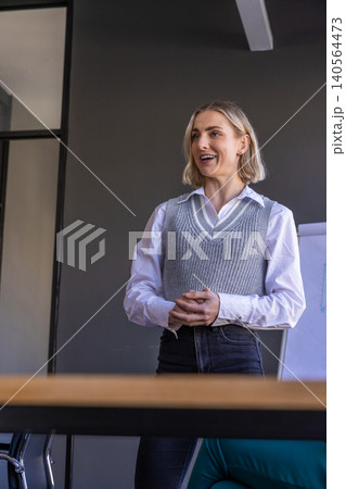 Professional woman standing and presenting at conference room table with flip chart Professional woman standing and presenting at conference room table with flip chart 140564473