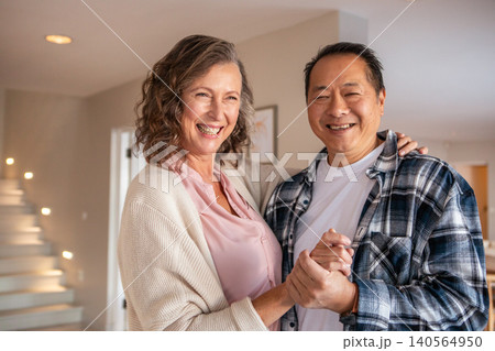 Diverse couple dancing holding hands in modern entryway near floating staircase, framed artwork 140564950