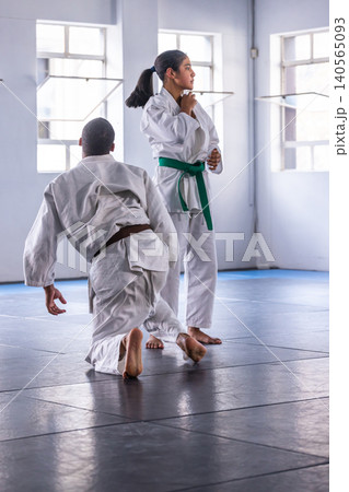 Diverse martial arts partners sparring on mats in dojo wearing white belted gis, copy space 140565093