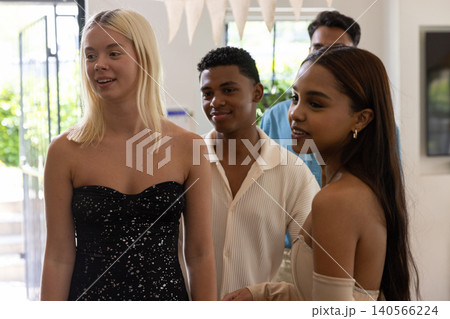 Diverse friends celebrating in decorated living room under pennant banners near glass door 140566224