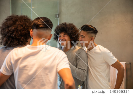 Diverse male friends standing at bathroom sink applying skincare pump bottle, tube in mirror Diverse male friends standing at bathroom sink applying skincare pump bottle, tube in mirror 140566334