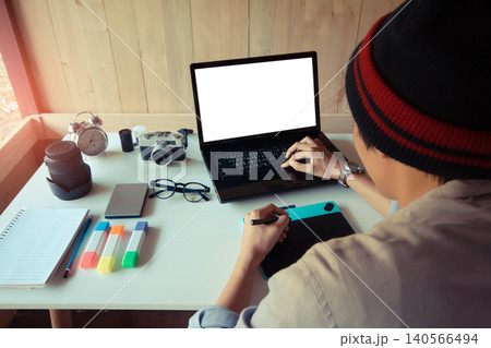 Back of freelance man graphic designer working on a digital laptop, with mock-up white screen for use. work from home office using a graphic tablet. Soft focus blur Back of freelance man graphic designer working on a digital laptop, with mock-up white screen for use. work from home office using a graphic tablet. Soft focus blur 140566494