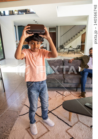 Indian father and son playing with virtual reality headset in living room on patterned rug Indian father and son playing with virtual reality headset in living room on patterned rug 140566748