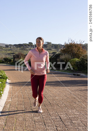 Female runner running on brick pathway in rural fields wearing athletic shoes, sportswear Female runner running on brick pathway in rural fields wearing athletic shoes, sportswear 140566786