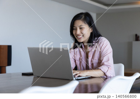 Asian korean woman typing on silver laptop in dining room with smartphone, copy space 140566800