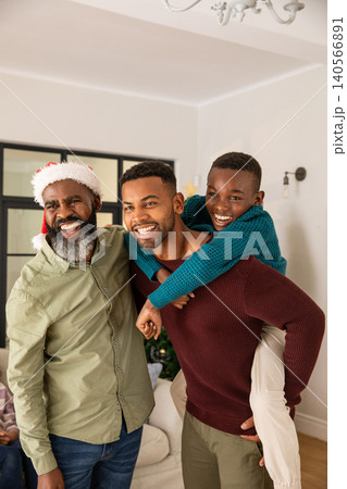 African american family standing and smiling in living room beside christmas tree in santa hat 140566891