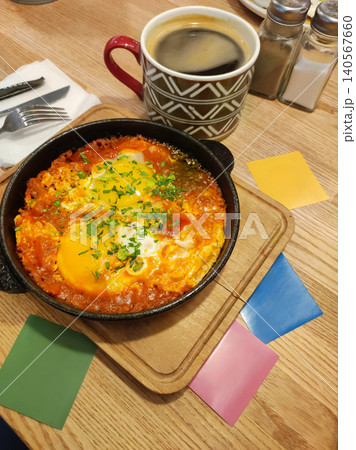 Traditional shakshuka in a cast iron skillet served with a cup of black coffee for breakfast. Traditional shakshuka in a cast iron skillet served with a cup of black coffee for breakfast. 140567660