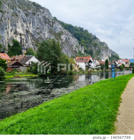Idyllic riverside village with limestone mountains in the background. Idyllic riverside village with limestone mountains in the background. 140567799